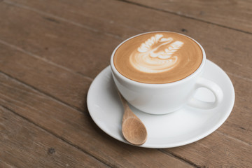 White cup of coffee on wooden table in the coffee shop.
