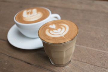White cup of coffee on wooden table in the coffee shop.