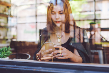 Woman using smart phone in a cafe,image of young woman sitting at a table with a coffee using mobile phone.