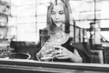 Woman using smart phone in a cafe,image of young woman sitting at a table with a coffee using mobile phone.