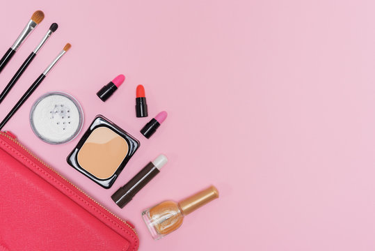 Makeup cosmetics palette and brushes on pink background flat lay