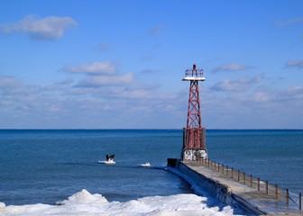 Lighthouse on a pier jutting out into an icy Lake Michigan in Chicago during winter.