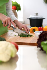 Closeup of human hands cooking vegetables salad in kitchen on the glass table with reflection. Healthy meal and vegetarian concept