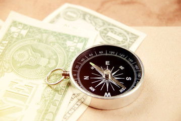 Magnetic compass with pocket money on work table, ready for traveling.
