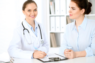 Friendly smiling doctor  and  patient sitting at the table. Very good news and high level medical service concept.