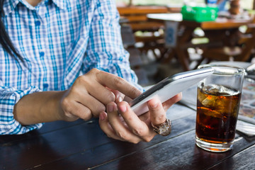 Women hand press mobile screen or smartphone and glass of soda
