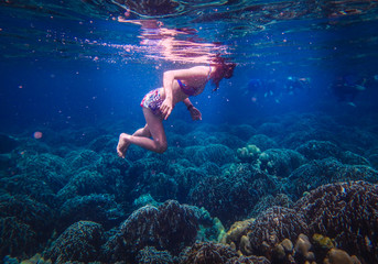 Underwater Photo of a Woman Diving , girl wearing bikini in action dive underwater ocean in thailand.
