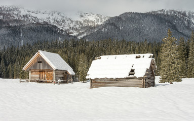 Old traditional shepherd cottage on alpine meadow during winter