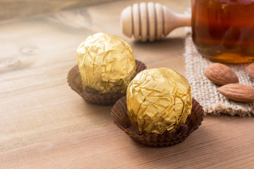 Chocolate ball in golden foil on wooden background, dessert in v
