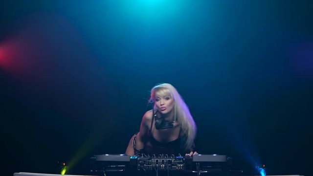 Dj woman blond dancing to the rhythm of playing music