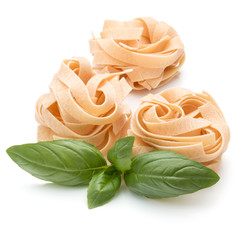 Italian pasta fettuccine nest and basil leaves  isolated on whit