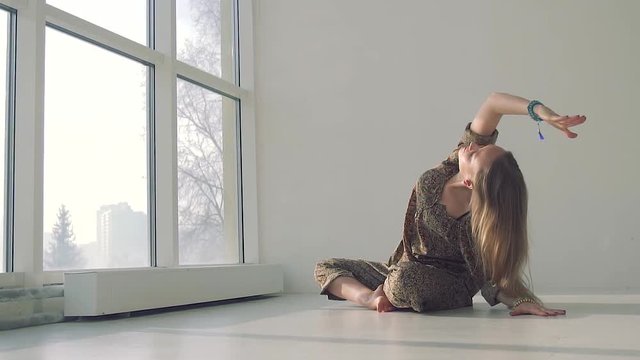 Young calm woman doing yoga in well-lit studio