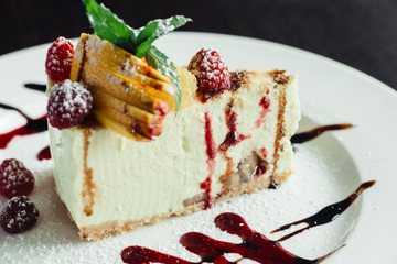 Philadelphia cake with raspberries and orange slice on white dish