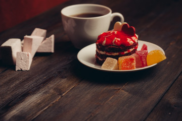 a cup of tea on the table, a biscuit biscuit with cream and jelly