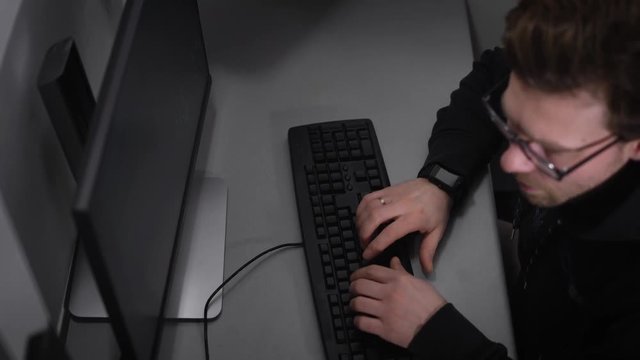 Top view of a man with glasses, who wore on his hand smart watches, body black sweatshirt, he was married, as put a ring on his finger. The man quickly typing the text on keyboard,