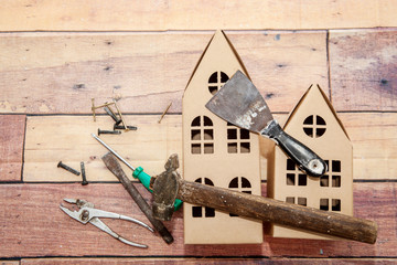 Decorative cardboard houses and repair tools on a wooden background