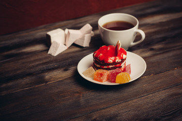 red cake on a saucer with marmalade cup of coffee and marshmallows