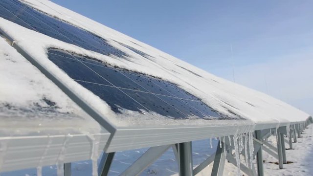 snow-covered solar panels on a sunny day snow is melting drops flow