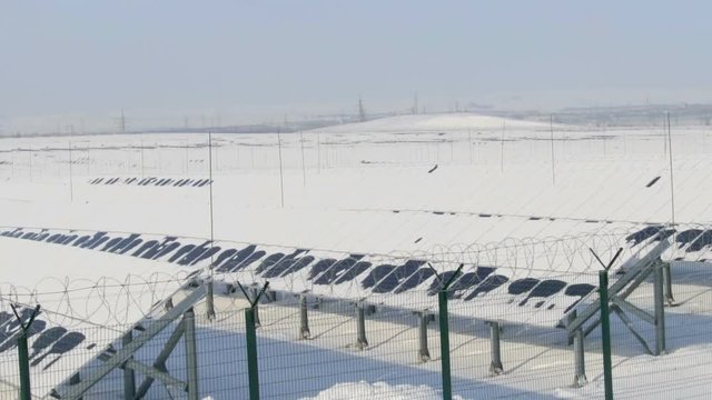 snow-covered solar panels on a sunny day pan view