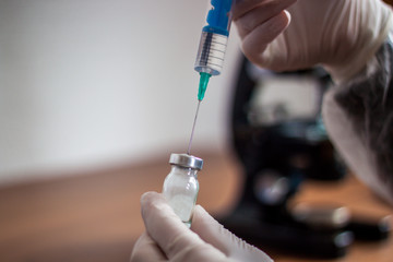 Young doctor prepares an injection to a patient, the injected li
