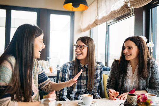 Beautiful female friends enjoy coffee talk in cafe bar