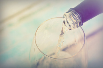 Glass of white wine being poured from bottle