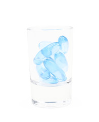 Shot glass full of softgel pills isolated