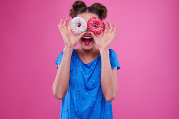 Merry woman looking through two sprinkled donutnuts