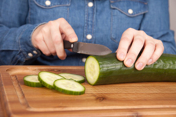 Frau schneidet Gurke in Scheiben