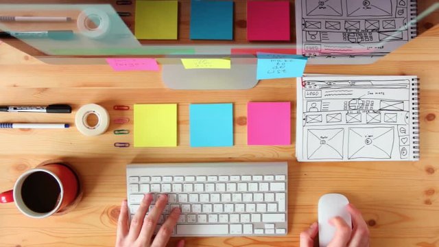 Top view to the workplace. The web master is working on the computer, making the site layout drawn on the sketch.