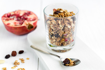 Homemade granola in a glass with pomegranate on white table