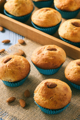 Sweet muffins with almond on blue wooden table.