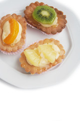 Tortine alla crema e frutta su piatto su sfondo bianco