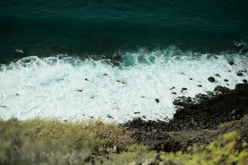 Beautiful aquamarine sea waves crash against black rocks