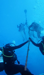 Scuba divers swimming to surface and holding onto rope