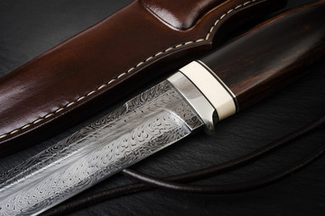 handmade knife Damascus of mosaic with a mammoth tusk on a black background