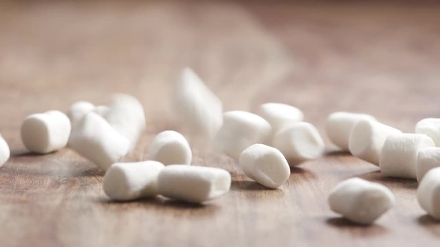 Slow motion of white marshmallow falling on wood table, 180fps prores footage