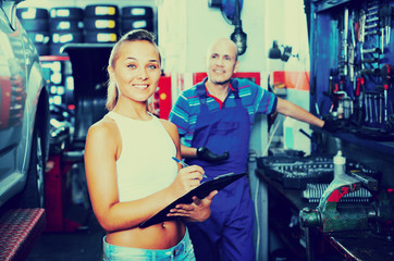 Woman standing and writing down data at car service