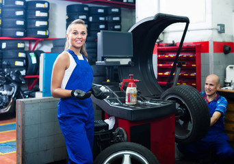 female technician standing with wheel balancing machinery at aut