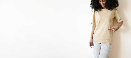 Cropped shot of beautiful young dark-skinned woman with charming pretty smile posing at blank white...
