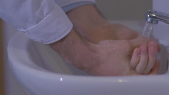 The doctor in a military hospital thoroughly wash their hands before surgery. Slow motion