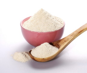 pile whole grain barley flour in bowl and wooden spoon isolated on white background