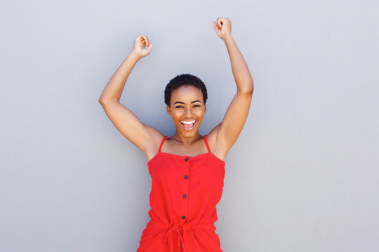 beautiful woman smiling with arms raised against gray background