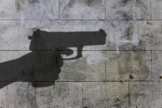 dark shadow of a hand holding a gun