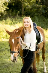 Foto op Canvas Молодая девушка со светлыми волосами стоит рядом с коричневой лошадью  © natasidorova 