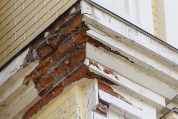 Corner house with crumbling plaster closeup. Urban