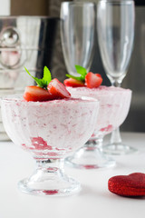 Strawberry mousse in a glass dish decorated with strawberry and lemon balm.