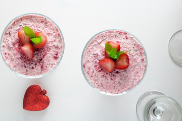 Strawberry mousse in a glass dish decorated with strawberry and lemon balm.