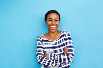 Fototapeta premium happy young black woman laughing against blue wall