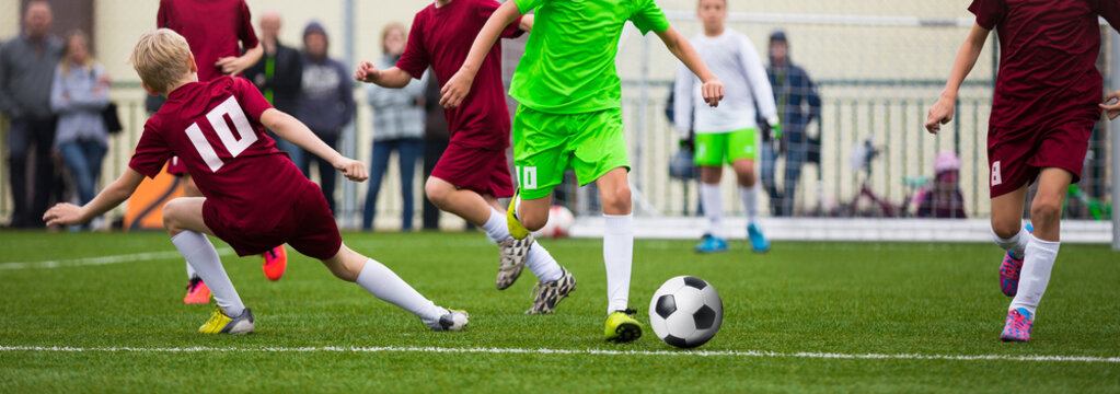Children Soccer Football Players. Footballers Kicking Football Match Game on the Grass. Young Soccer Players Running After the Ball. Horizontal Youth Sports Background